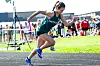 Female athlete running on a track with spectators behind her.