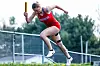 Runner in red uniform sprinting with a baton.
