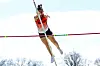 Athlete in mid-air clearing the pole vault bar.