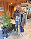 Two people pose with a plant and a sign promoting conservation.