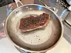 Seared steak in a stainless steel pan.