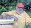 Beekeeper in yellow suit next to a beehive.