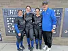 Softball players and coach pose in front of a wall.