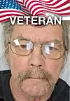 Close-up of a veteran with glasses and mustache against an American flag.