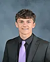 Young man in a suit with a purple tie smiling for a portrait.