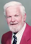 Smiling older man with a beard in a red blazer.