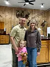 Family posing in a rustic room with wooden walls.