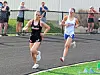 Two female runners competing on a track.