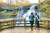 Visitors at a waterfall in autumn.