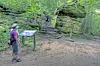 Hiker looking at a sign near a rock formation in a forest.