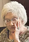 Elderly woman with glasses in a thoughtful pose.