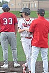 Baseball player shakes hands with coach on the field.