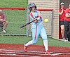 Player in blue uniform swings at a softball.