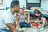 Father and children playing together in a bedroom.