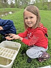 Girl holding a small creature by a pond.