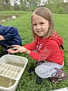 Girl holding a small creature by a pond.