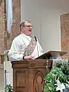 Clergy member at pulpit delivering a sermon.