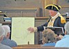 Presenter in costume shows a map to an audience.