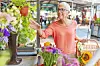 Woman with glasses shopping for flowers at a market.