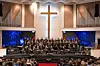 Choir performing on stage in a church.