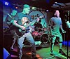 Band performing live with instruments and colorful lights.