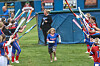 A young girl runs through teammates holding bats.