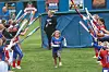 A young girl runs through teammates holding bats.