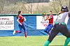 Two softball players in red uniforms catching a ball.