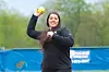 Athlete throwing a yellow softball on a practice field.
