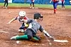 A player sliding into home plate in a softball game.