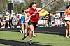 Male athlete running with a pole in a track event.