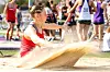 Female athlete in red jumps into sand pit.
