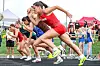 Runners in colorful uniforms starting a race on a track.