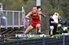 Female athlete jumping over a hurdle in red uniform.