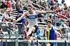 Athlete jumping over a hurdle at a track event.