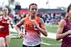A runner in an orange jersey competing in a track event.