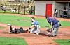 Baseball player sliding into home plate while catcher attempts to tag.