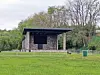 Outdoor stage with stone columns and a grassy area.