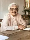 Elderly woman smiling at a table.