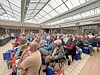 Audience seated in a bright indoor venue during a community event.