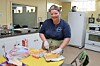 Volunteer slicing cheese in a kitchen setting.