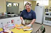 Volunteer slicing cheese in a kitchen setting.