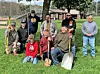 Volunteers with shovels and tools in a park setting.