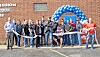 Group of people at a ribbon-cutting ceremony outside a building.