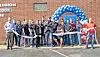 Group of people at a ribbon-cutting ceremony outside a building.
