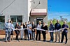 Group of people at a ribbon-cutting ceremony outside a building.