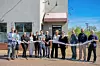 Group of people at a ribbon-cutting ceremony outside a building.