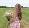 Woman with flowers in a green field.