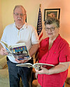 Elderly couple reading books in a living room.