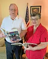 Elderly couple reading books in a living room.